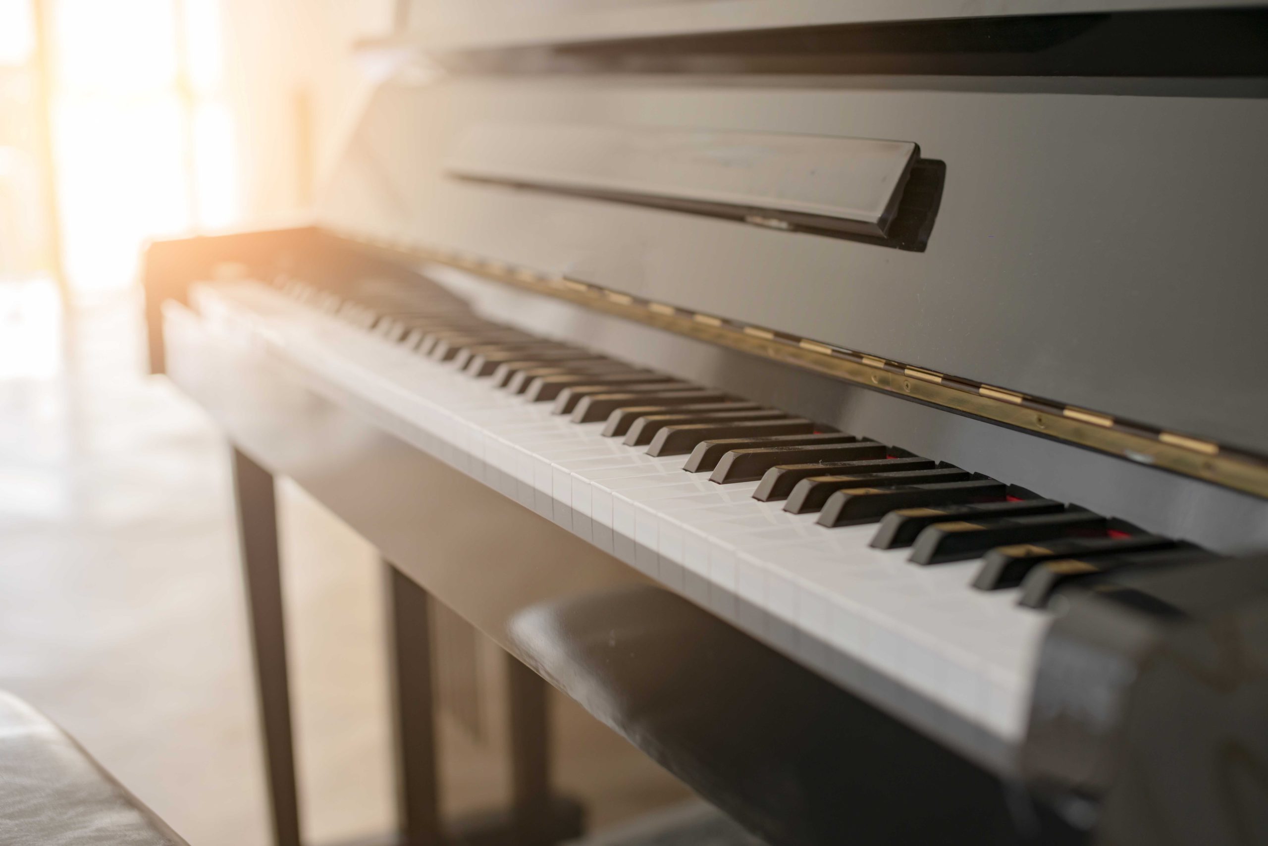 black shiny piano with sun light from white curtain window